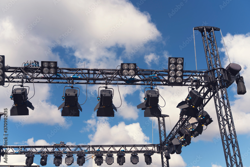Installation of professional sound, light, led panel, video and stage equipment for a concert. Stage lighting equipment is clamped on a truss for lifting. Flight cases with cables.. Stock | Adobe