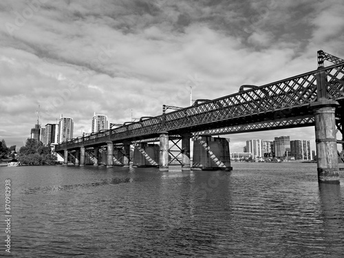Beautiful black and white view of a railway bridge across a river on a sunny day with light clouds, Parramatta river, Meadowbank, Sydney, New South Wales, Australia