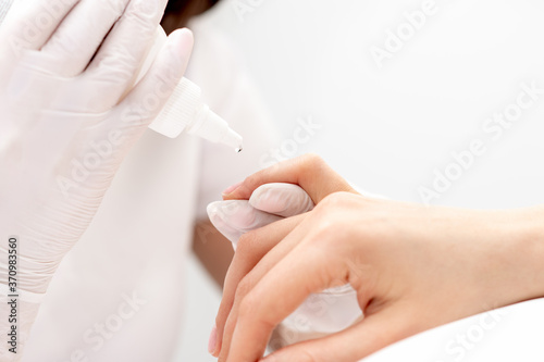 Professional manicurist pouring oil on nails manicure of woman in beauty salon.