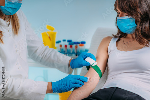 Medical worker with PPE taking blood sample from patient in a hospital photo