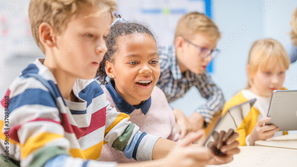 Elementary School Computer Science Class: Children Use Digital Tablet Computers and Smartphones with Augmented Reality Software, They’re Excited, Full of Wonder. Children in STEM, Playing and Learning Elementary School Computer Science Class: Children Use Digital Tablet Computers and Smartphones with Augmented Reality Software, They’re Excited, Full of Wonder. Children in STEM, Playing and Learning