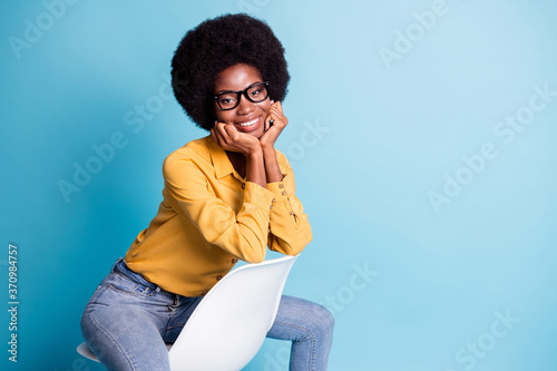 Photo of attractive charming dark skin girl sit white chair touch hands chin wear good look clothes isolated over blue color background © deagreez