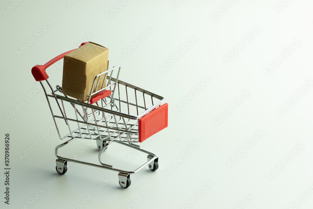 Shopping cart with brown box inside on white background with copy space. Online digital store concept