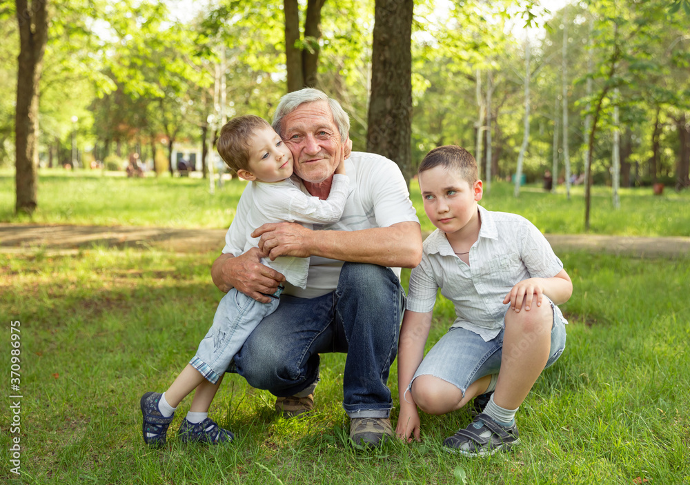 Senior man and grandsons are hugging and smiling, resting together