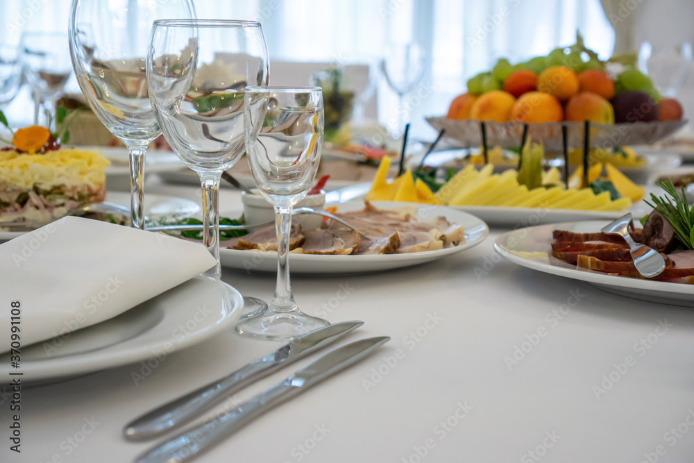 beautiful table setting in light colors with dishes and assorted food on a table with a white tablecloth for a party, wedding or other special event. Restaurant business and service industry concept.