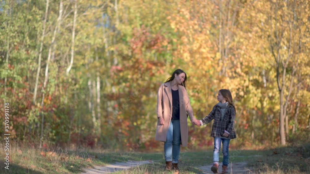 Happy mom walks with her daughter in the autumn park. The family is walking in the autumn park. happy childhood concept. Happy mom walks with her daughter in the autumn park. The family is walking in the autumn park. happy childhood concept.