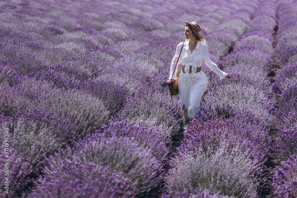 A young woman is enjoying a bright sunny day in the field of blooming lavender A young woman is enjoying a bright sunny day in the field of blooming lavender