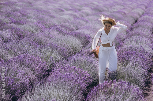 A young woman is enjoying a bright sunny day in the field of blooming lavender