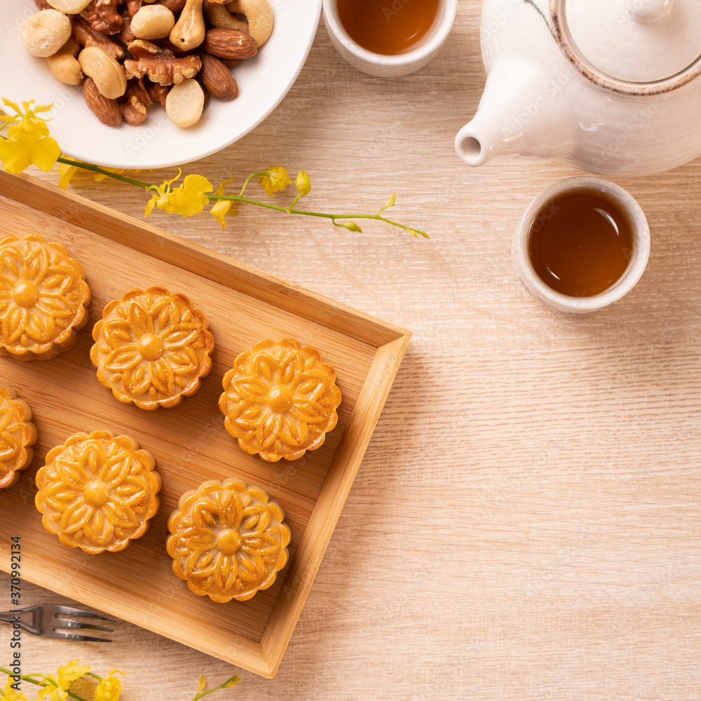 Fototapeta premium Mid-Autumn Festival holiday concept design of moon cake, mooncakes, tea set on bright wooden table with copy space, top view, flat lay, overhead shot
