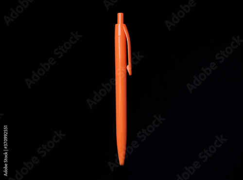 Orange pen on black background. Copy space, isolated.