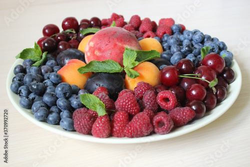 Fresh berry mix on a light background on a white plate .Texture or background