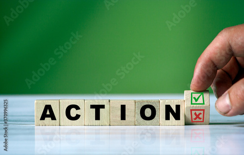 The hand turns the wooden cube and changes the word ACTION