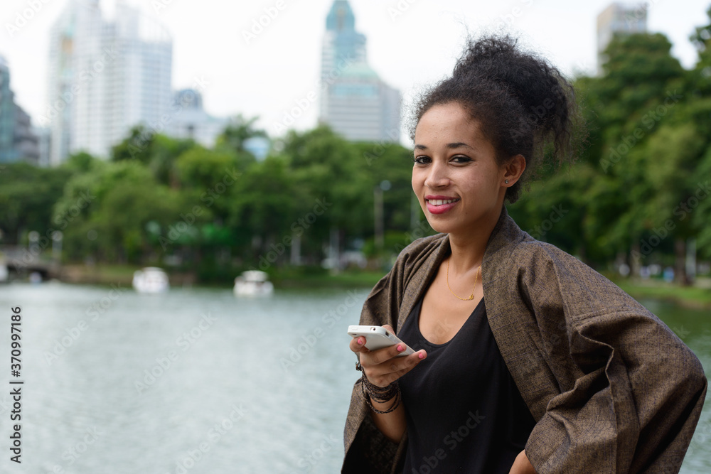 Portrait of happy young beautiful African woman using phone at the park Portrait of happy young beautiful African woman using phone at the park