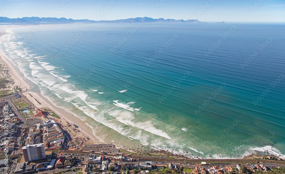 Cape Town, Western Cape / South Africa - 06/30/2020: Aerial photo of surfers and waves at Muizenberg Beach