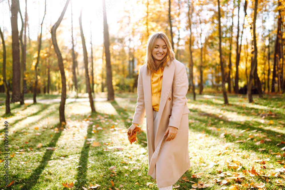 Smiling woman playing with autumn yellow leaves. Stylish woman enjoying autumn weather in the park. Smiling woman playing with autumn yellow leaves. Stylish woman enjoying autumn weather in the park.