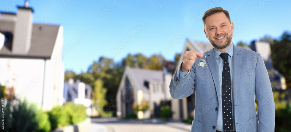 Real estate agent with key against modern houses, space for text. Banner design Real estate agent with key against modern houses, space for text. Banner design