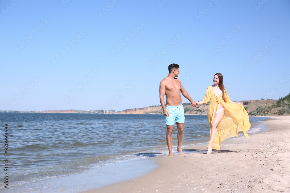 Woman in bikini and her boyfriend on beach, space for text. Happy couple Woman in bikini and her boyfriend on beach, space for text. Happy couple