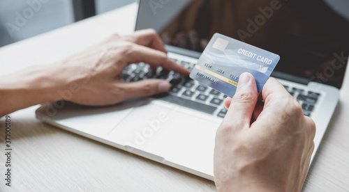 Businessman hand hold credit card to online shopping on laptop computer from home, payment e-commerce, internet banking, spending money