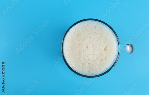 Delicious homemade kvass in glass mug on light blue background, top view. Space for text