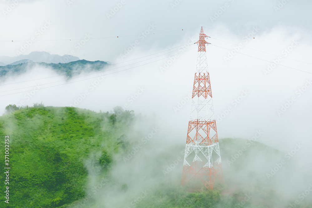 High voltage transmission towers on mountain with fog.
