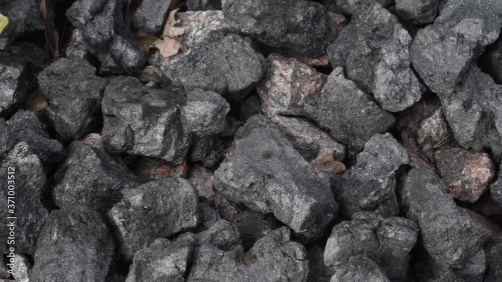 Background with a pile of coal mixed with granite cobblestones and leaves. Concept - non-renewable natural fuel and energy Background with a pile of coal mixed with granite cobblestones and leaves. Concept - non-renewable natural fuel and energy