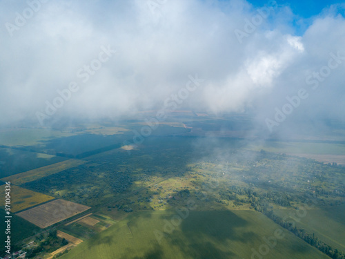 High flight in the clouds over agricultural fields. © Sergey
