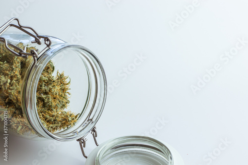 Open jar with cannabis buds. Dry marijuana for medical use. Weed concept design for web site template. White background with copy space. Mockup on thc theme