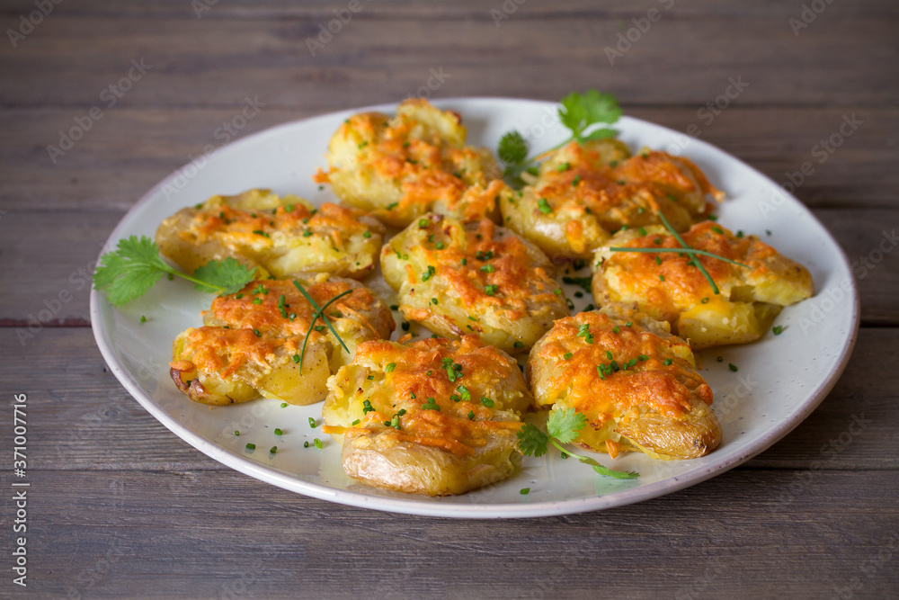 Smashed new baby potatoes with garlic butter and cheese on wooden background close up. Clean eating Smashed new baby potatoes with garlic butter and cheese on wooden background close up. Clean eating