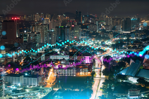 FOREX graph hologram, aerial night panoramic cityscape of Kuala Lumpur. KL is the developed location for stock market researchers in Malaysia, Asia. The concept of fundamental analysis. © VideoFlow