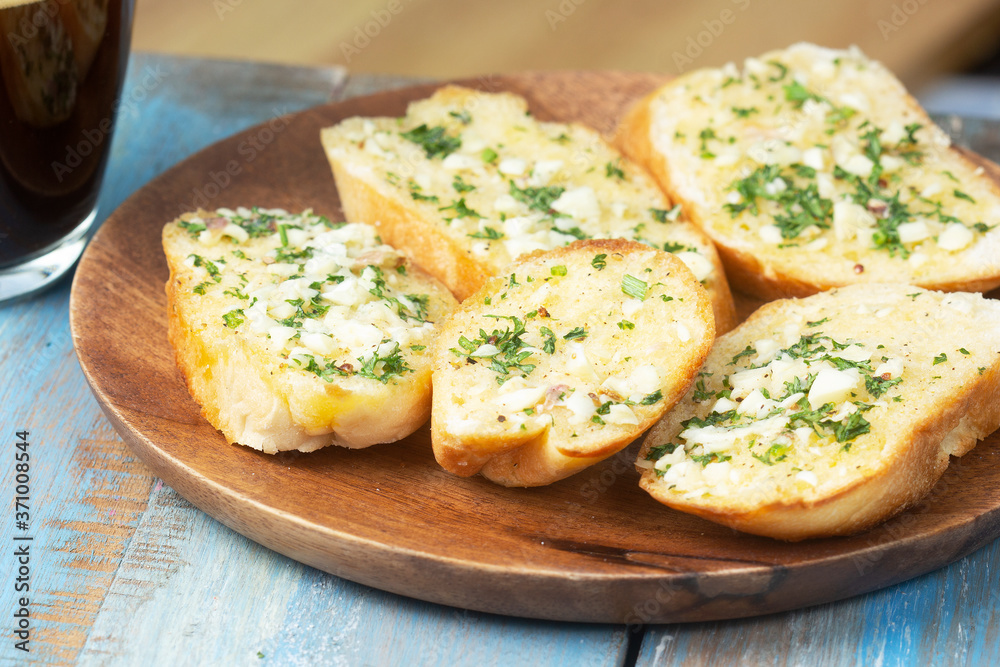Garlic bread on the wooden plate with black coffee