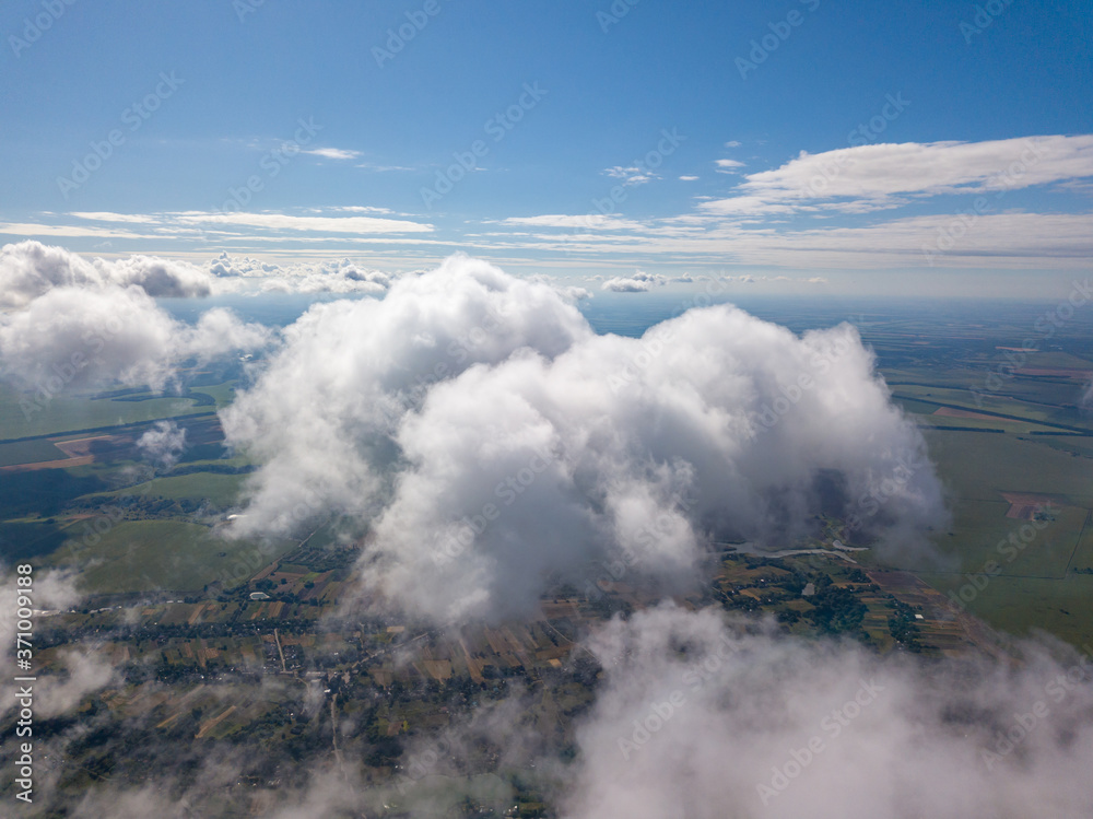 Fototapeta premium High flight in the clouds over agricultural fields.
