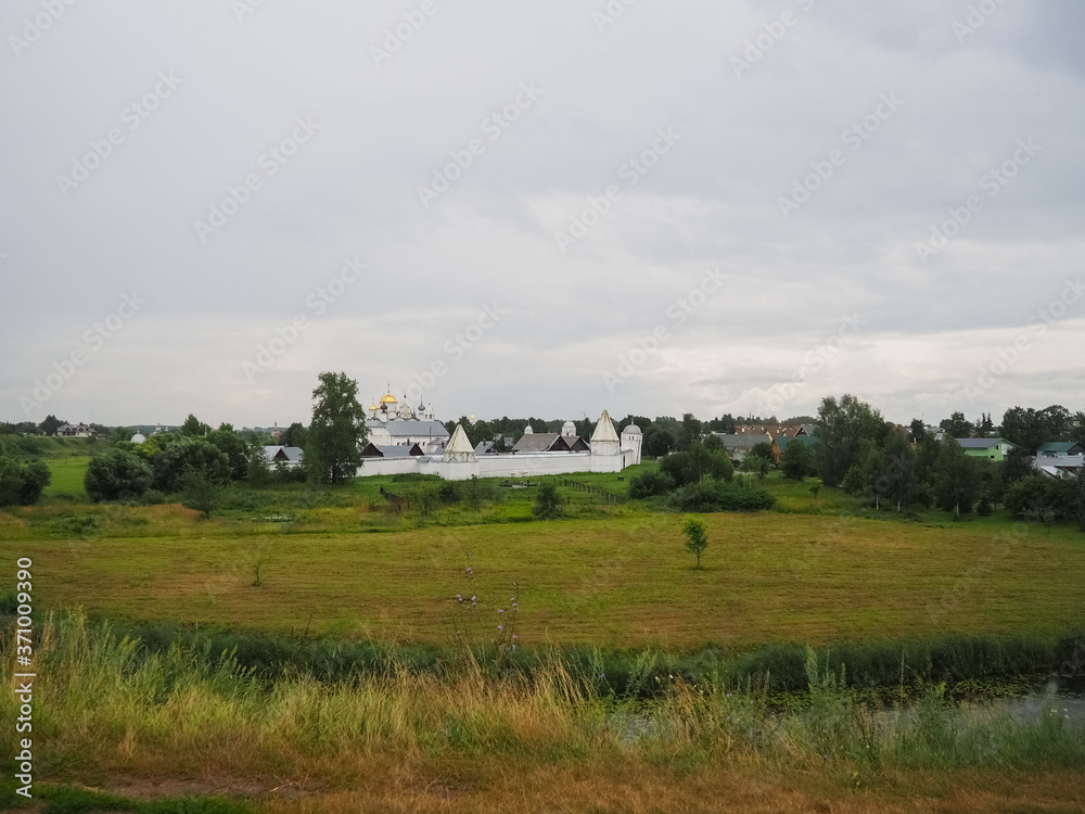 photo of a large field and a wide river in Suzdal in cloudy weather photo of a large field and a wide river in Suzdal in cloudy weather