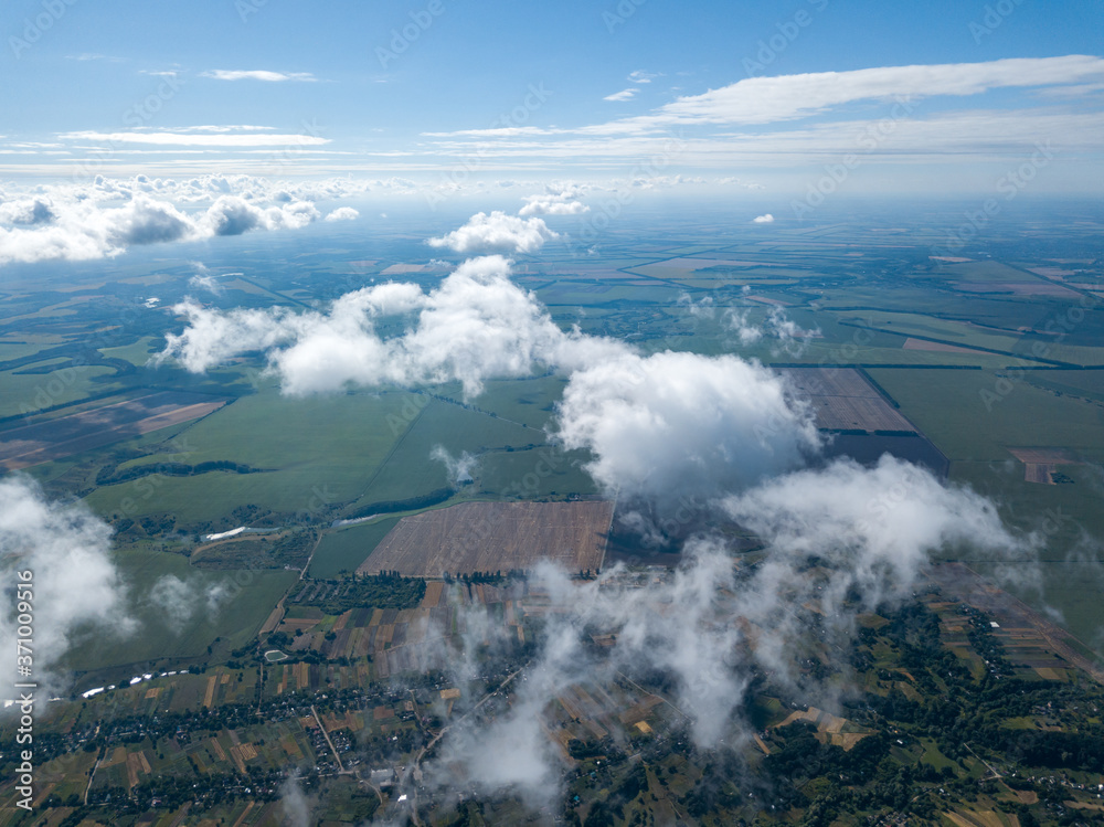 Fototapeta premium High flight in the clouds over agricultural fields.