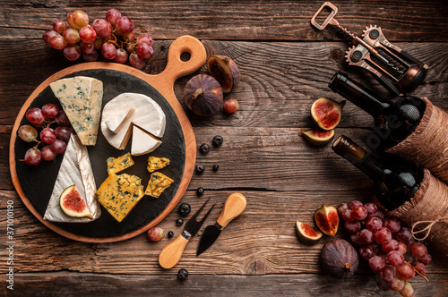 food composition with assorted cheese, glass of wine and fruits on a wooden table. banner, catering menu recipe place for text, top view