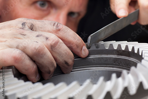 Fotografía Close-up of hands of a mechanic repairing a cog wheel with a rasp