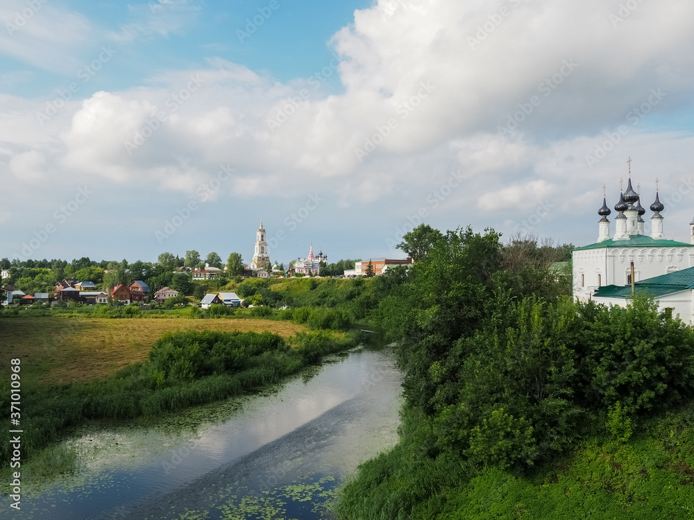 photo of the wide Suzdal river near Russian white stone Orthodox churches