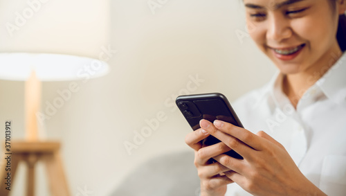 Young woman hand holding smartphone and chatting with friends at social network on the table.