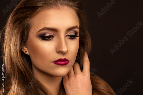 Amazing young woman looking down with bright make up. Perfect skin and beautyful hair. Red lips