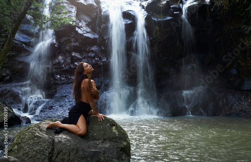 girl sitting on the background of a waterfall.