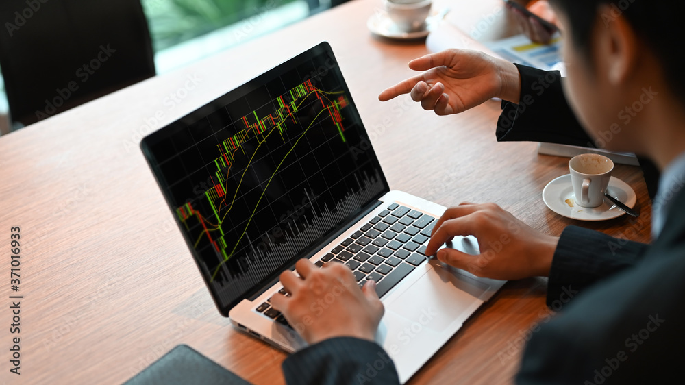 Business People are using a computer laptop with a candlestick chart on-screen at the meeting table. Business People are using a computer laptop with a candlestick chart on-screen at the meeting table.