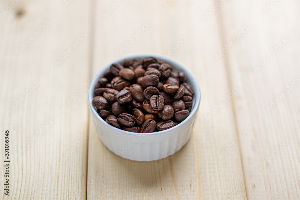 Fototapeta premium White mug with Cup of coffee beans on wooden background with selective focus and crop fragment