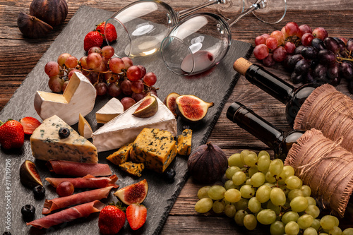 Fototapeta Naklejka Na Ścianę i Meble -  still life, food composition with assorted cheese, glass of wine and fruits on a wooden table