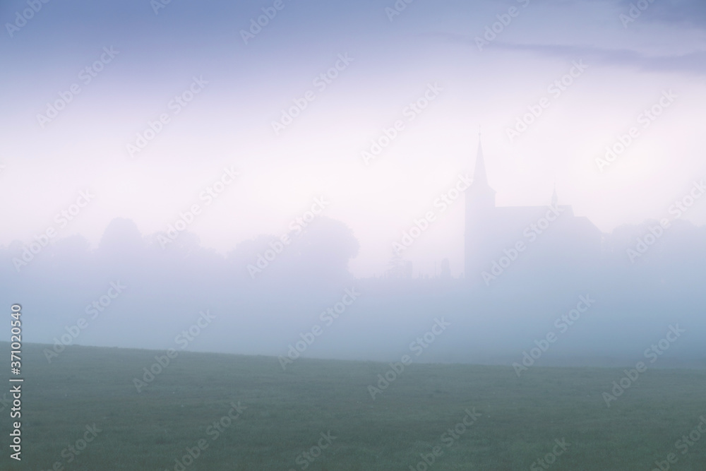 Small church in foggy morning. Summer misty time.