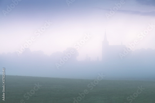 Small church in foggy morning. Summer misty time.