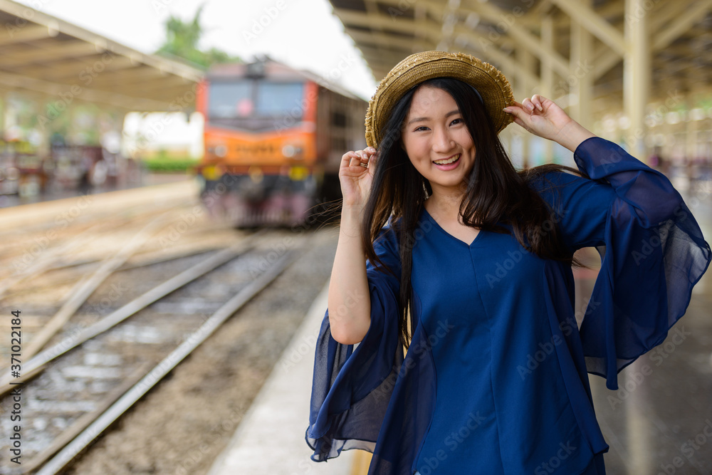 Happy young beautiful Asian tourist woman at the railway station
