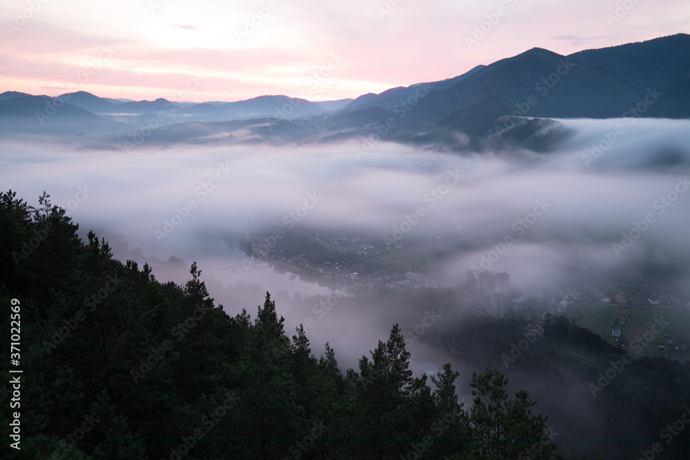 Obraz premium Beautiful autumn scenery of foggy valley in mountains at early morning before sunrise. Hill with trees on foreground. Fabulous sunrise on Germany, Europe. Beauty of nature concept background.