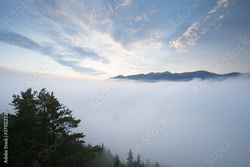 Beautiful autumn scenery of foggy valley in mountains at early morning before sunrise. Hill with trees on foreground. Fabulous sunrise on Germany, Europe. Beauty of nature concept background. 