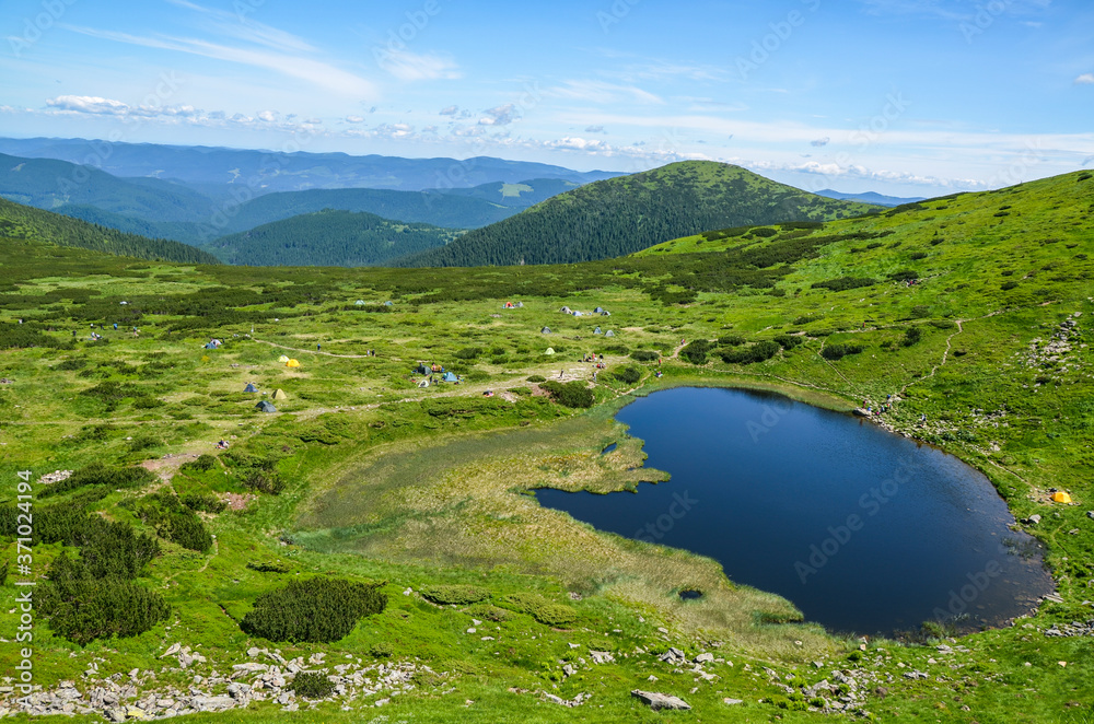 Panorama view from the height, to Alpine lake Nesamovyte under hill among a green mountains of Chornohora Ridge, Ukraine