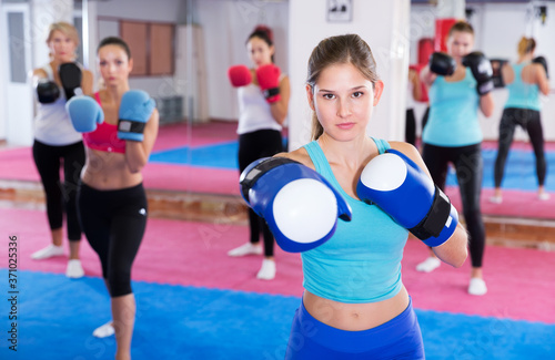 Portrait of sporty female who is training box exercises in group in sporty gym.