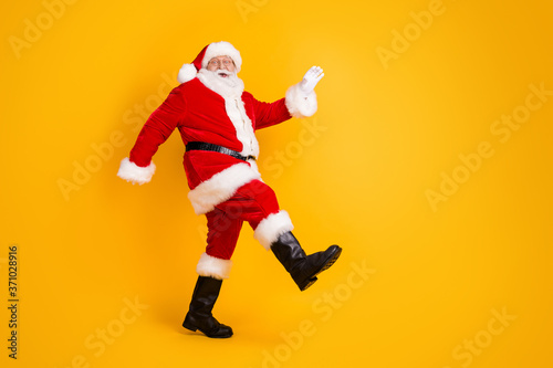 Full length body size profile side view of his he nice funny cheerful thick white-haired Santa St Nicholas going dancing having fun isolated bright vivid shine vibrant yellow color background